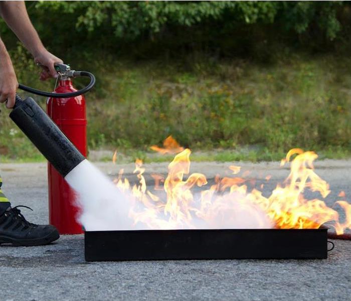 Red fire extinguisher putting out a controlled fire in a black box